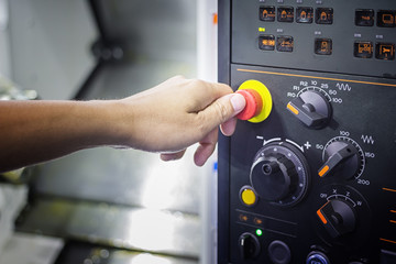 A Thumb ready to press emergency Stop button on Control panel of CNC machine