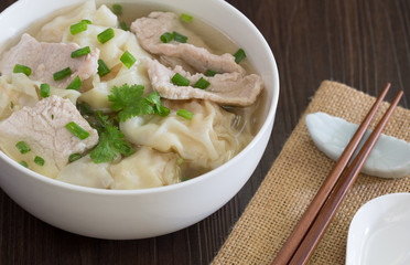 Shrimp wonton with braised pork in soup on wooden table / Select focus image ..