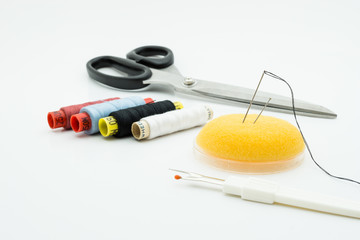 Fototapeta na wymiar Scissor, seam ripper, sewing needle and threads over white background