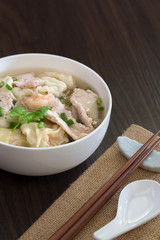 Shrimp wonton with braised pork in soup on wooden table / Select focus image and space for text..