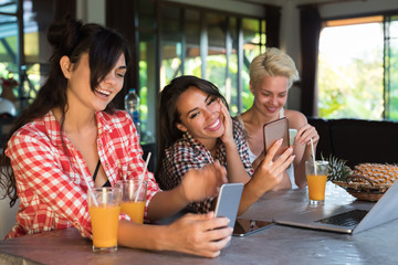 Three Girls Sitting At Table Use Cell Smart Phones Happy Smiling, Young Woman Chatting Online Friends Together Media Communication Concept