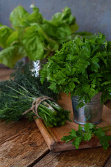 Composition of green herbs and vegetables. Organic spring mix for salad on brown wooden background. Lettuce, parsley, dill, chard.