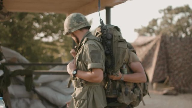 American soldier helps another to pack equipment on the military campaign