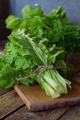 Freshly organic picked green swiss chard on wooden background. Spring green herbs