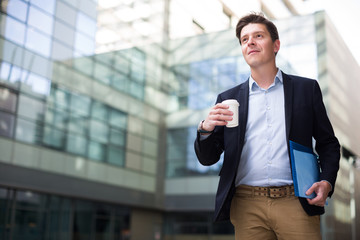 Professional man in jacket walking with coffee