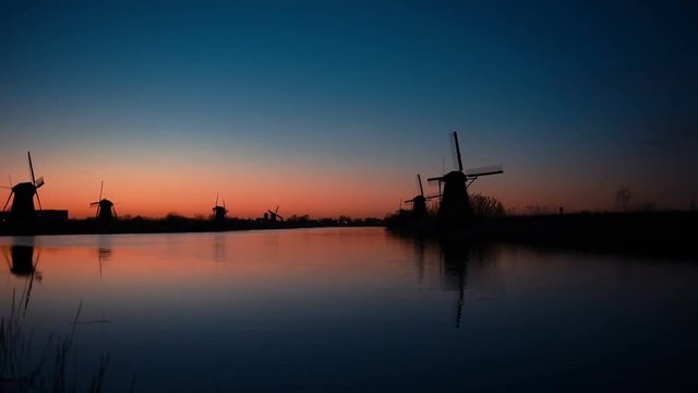 Traditional Dutch windmills from the channel Rotterdam at sunset. Water mirror effect. Holland.