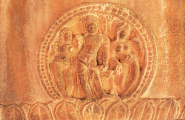 Fototapeta na wymiar Man and two woman figures on stone wall relief of 7th century Hindu temple, town Aihole, India. Carved architecture of Asia.