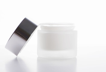 Close-up of bottle of skin cream.Next to the lid on white background. Isolated.
