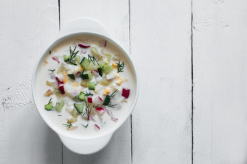 Okroshka. Traditional russian Summer yoghurt cold soup with vegetables. Wooden background