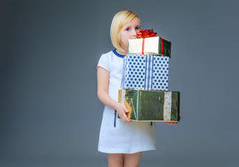 modern child on grey holding pile of christmas present boxes