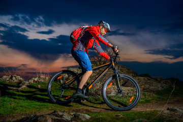 Fototapeta na wymiar Cyclist Riding Mountain Bike on Spring Rocky Trail at Beautiful Sunset. Extreme Sports and Adventure Concept.