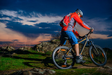 Fototapeta na wymiar Cyclist Riding Mountain Bike on Spring Rocky Trail at Beautiful Sunset. Extreme Sports and Adventure Concept.