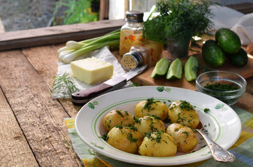 Organically grown new potatoes with butter and dill on wooden background. First spring harvest.