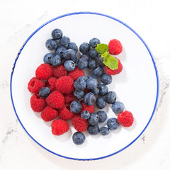 plate with berries on a white background, closeup top view
