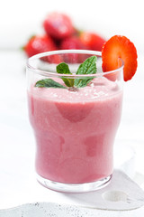 refreshing strawberry milkshake on white table, vertical closeup