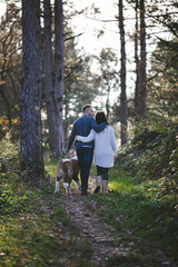 Naklejka na ściany i meble Young couple enjoying nature outdoors together with their adorable Saint Bernard puppy. People and dogs theme.