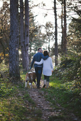 Fototapeta premium Young couple enjoying nature outdoors together with their adorable Saint Bernard puppy. People and dogs theme.