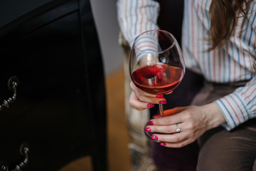 Female hand holding glass of red wine closeup