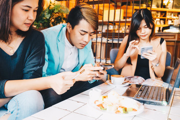 Fototapeta premium Group of three young business people gathered together with laptop at a table discussing
