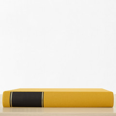 Yellow book with black frame on spine on the table near the white wall - 155827005