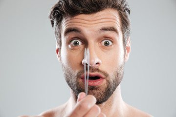 Shocked man with tweezer looked camera