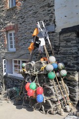 Lobster pots, buoys and marker flags next to a stone house in a traditional  English fishing port - obrazy, fototapety, plakaty
