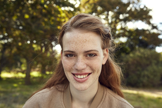 Portrait of smiling redheaded young woman with freckles