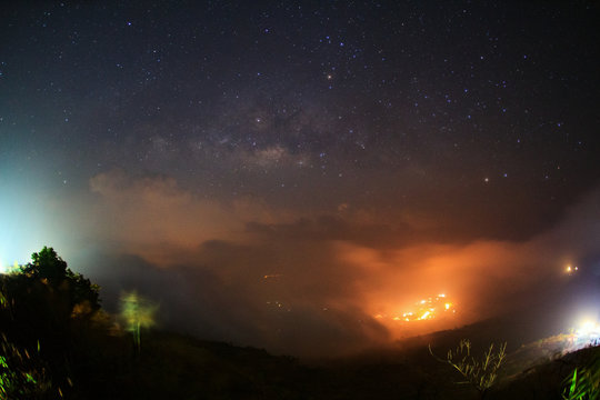 Milky way galaxy with cloud and city light at Phutabberk Phetchabun in Thailand.Long exposure photograph.With grain