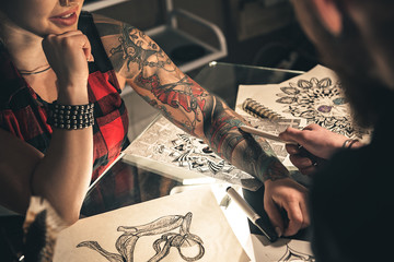 Female hand with tattoo situating on desk - obrazy, fototapety, plakaty