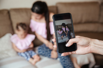 Mother with daughter sitting while anyone photographing their