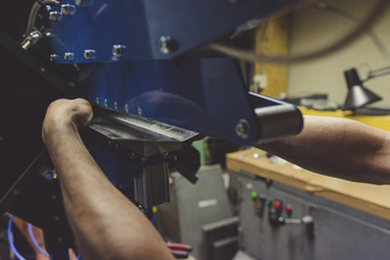 Man working in a workshop, bending aluminum sheets - obrazy, fototapety, plakaty