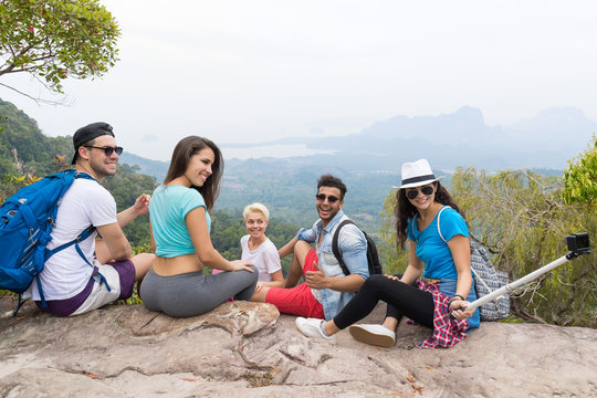 People Group With Backpacks Sitting On Mountain Top Taking Selfie Photo, Young Men And Woman Tourists Backpackers On Hike