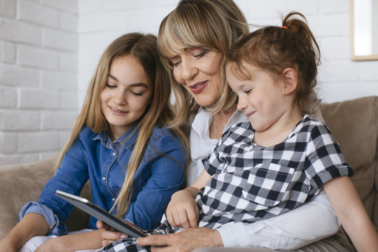 Woman with two granddaughters looking at tablet