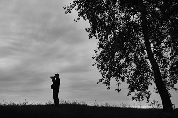 Silhouette of a photographer in a field near a tree