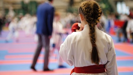 Karate girl in a white kimono with red belt ready to fight