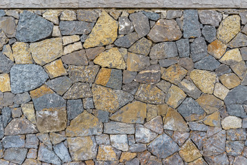 Detail of grey and yellow rocks used as a wall