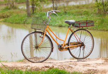 Fototapeta na wymiar An old bicycle in meadow during sunset with shallow dept of field
