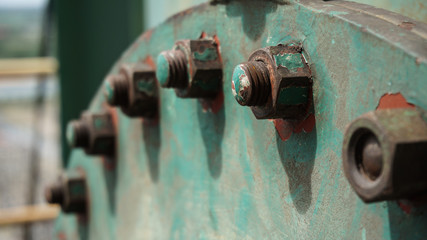 Rusty bolts on a old green metal plate, close-up.