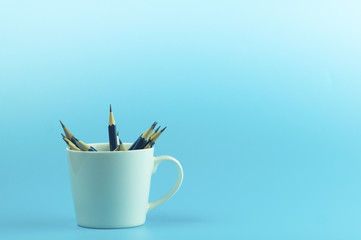 pencils in white cup with on blue background