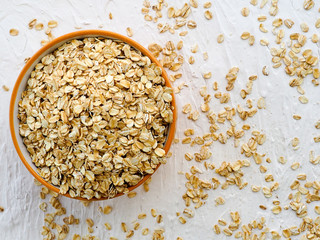 Dry rolled oatmeal in bowl on white background. Top view. space for text