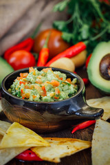 Guacamole with corn chips - nachos, made from avocado, tomatoes and lime.