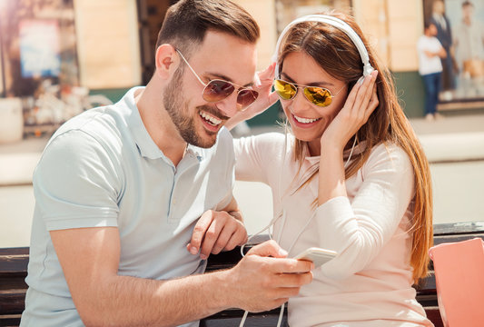 Young smiling couple listening to music with mobile phone and headphones. Dating, love and tenderness, lifestyle concept