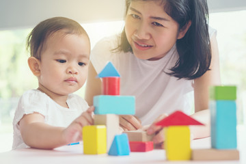 Asian mom and girl kid playing with blocks. Vintage effects and soft light.