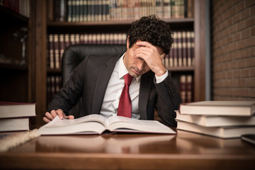 Portrait of a tired businessman reading a book