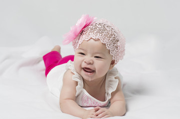 Cute little Asian baby girl lying on white background