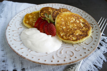 Cottage cheese pancakes with sour cream and strawberries.