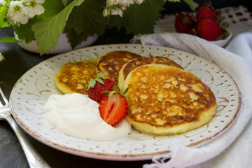 Cottage cheese pancakes with sour cream and strawberries.