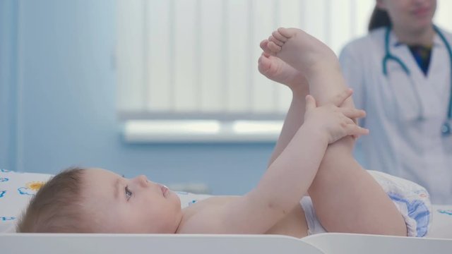 Cute little boy lays on the nappy and touch his legs