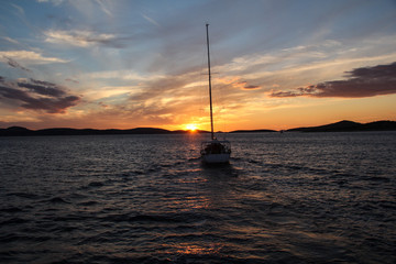 Sailing cruise on a small luxury yacht towards the sunset in the Adriatic Sea of the Croatia coast near Sibenik