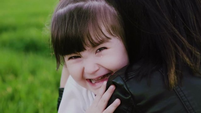 Cute sad little girl, embracing her mother and cry hardly to camera